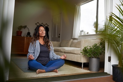 Mature woman meditating while practicing yoga in her living room